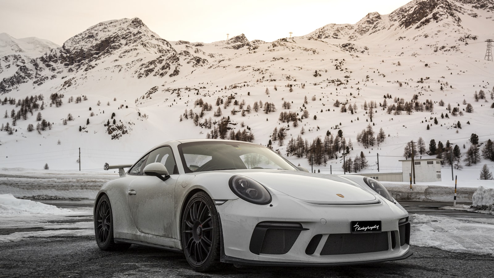 A grey Porsche 992 GT3 Touring photographed from the rear three-quarter on a residential street