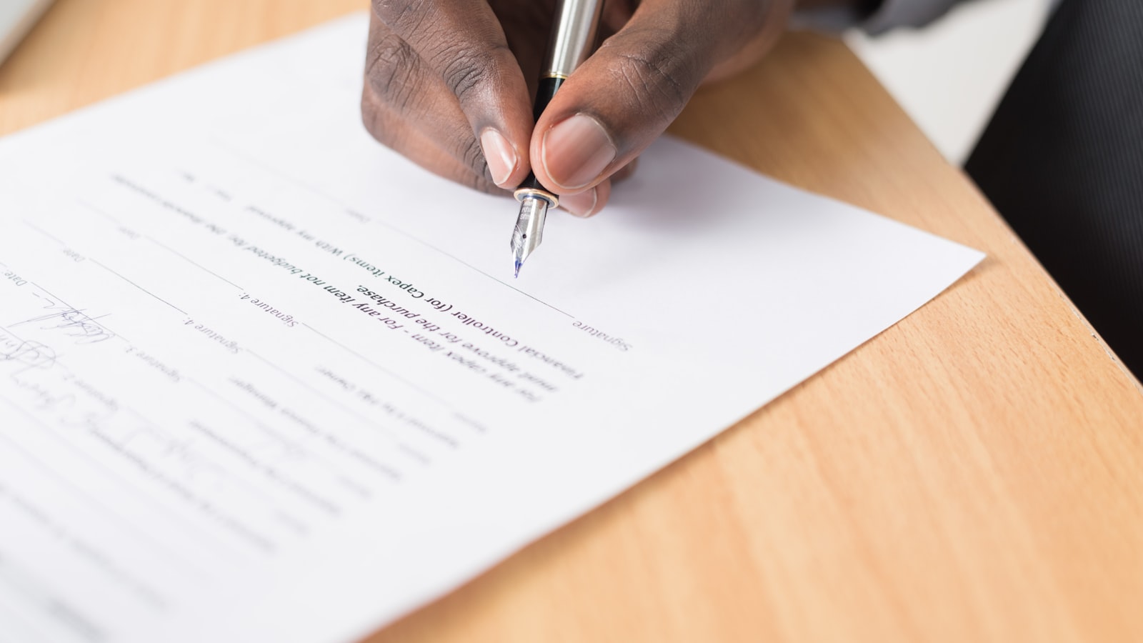 Paperwork and a fountain pen photographed on a wooden desk