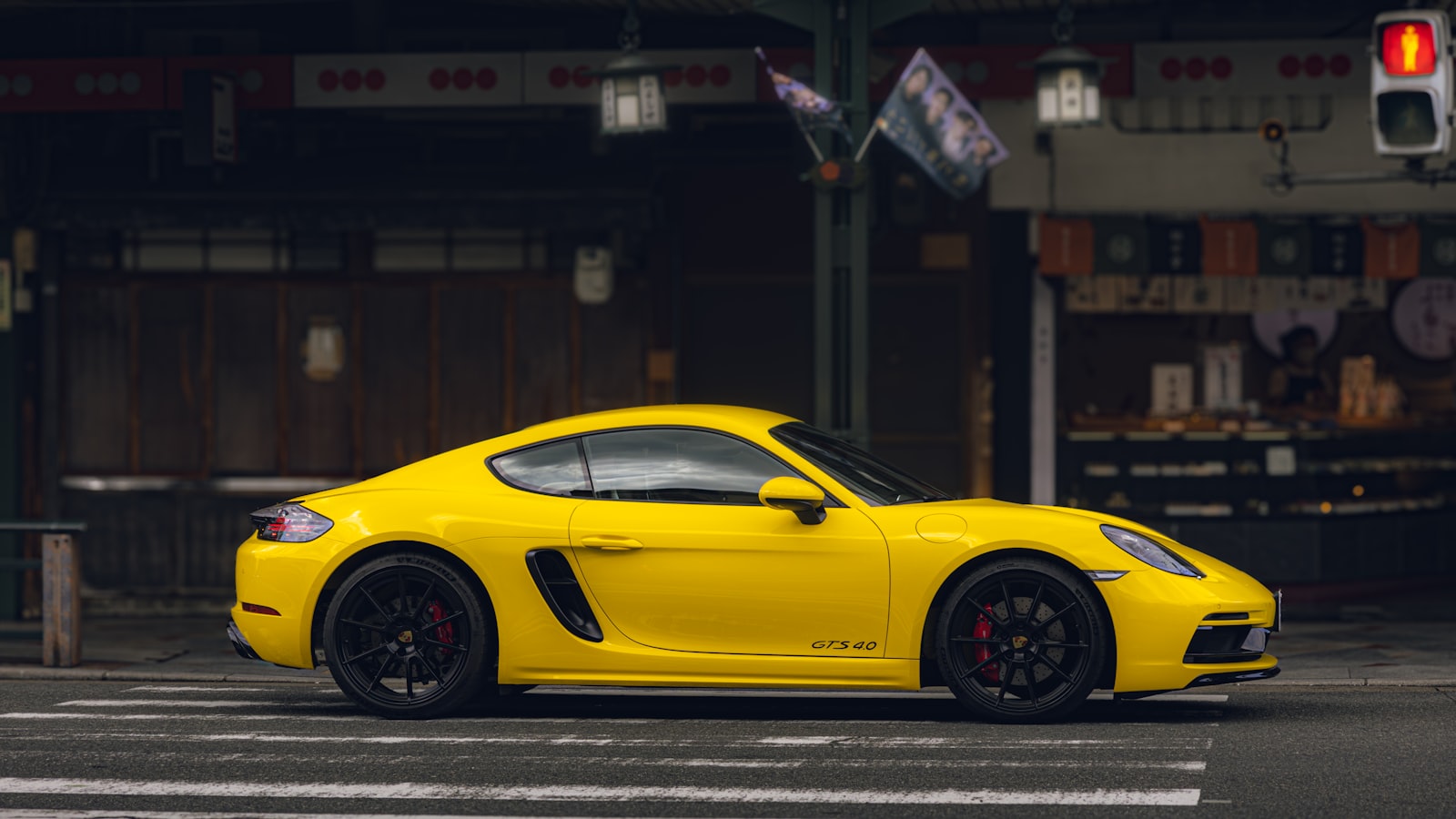 A yellow Porsche 911 with RUF-style aero, parked in front of an open garage